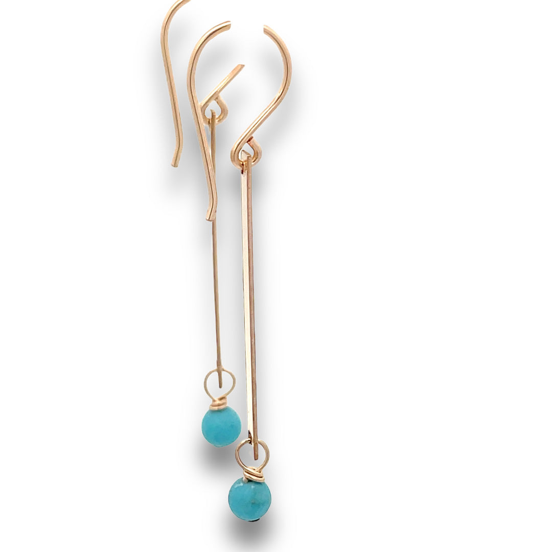 side view  of gold bar and turquoise earrings on a white background.